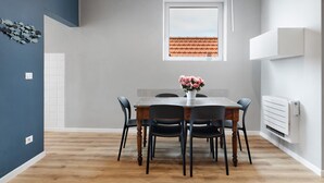 Un comedor con una mesa, sillas, un florero, una ventana y un radiador.