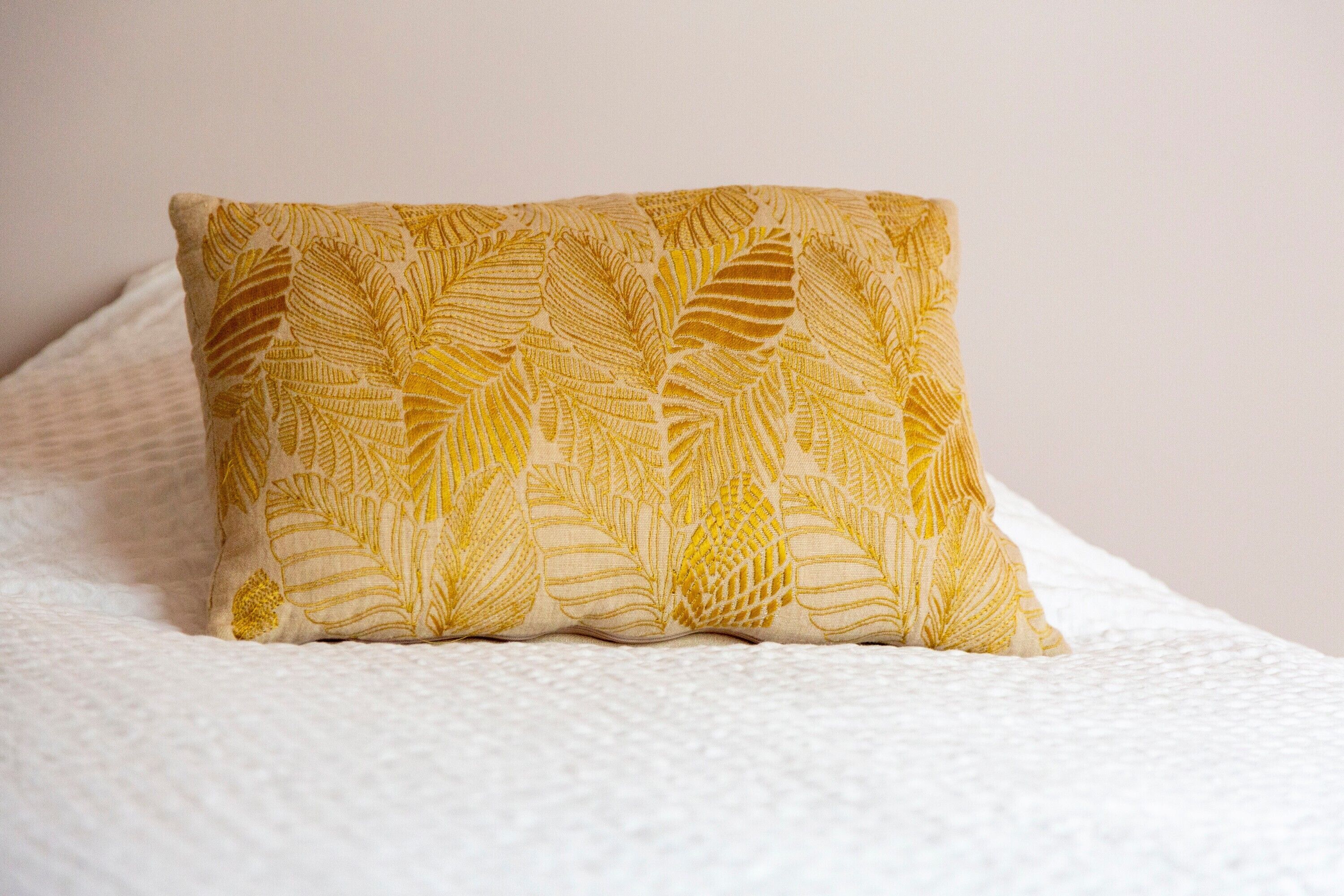A pillow with a leaf pattern on a bed.