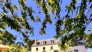 Une maison avec un jardin, une pelouse et un parasol rouge.