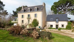 Une maison à deux étages avec une façade en pierre, un balcon et un petit jardin.