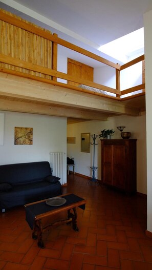 Un espace de vie de style loft avec un plafond en bois, un canapé noir, une table basse en bois et un radiateur.