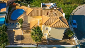 Una propiedad residencial con piscina, un patio cubierto y un vehículo estacionado en la calle.