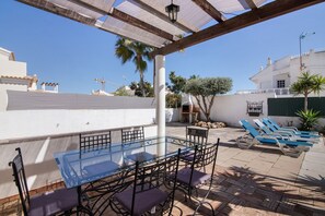 A patio with a glass table and chairs, a pergola, and lounge chairs. - Holiday Home 'Breeze - Adults Only' with Sea View, Wi-Fi and Air Conditioning (Albufeira)