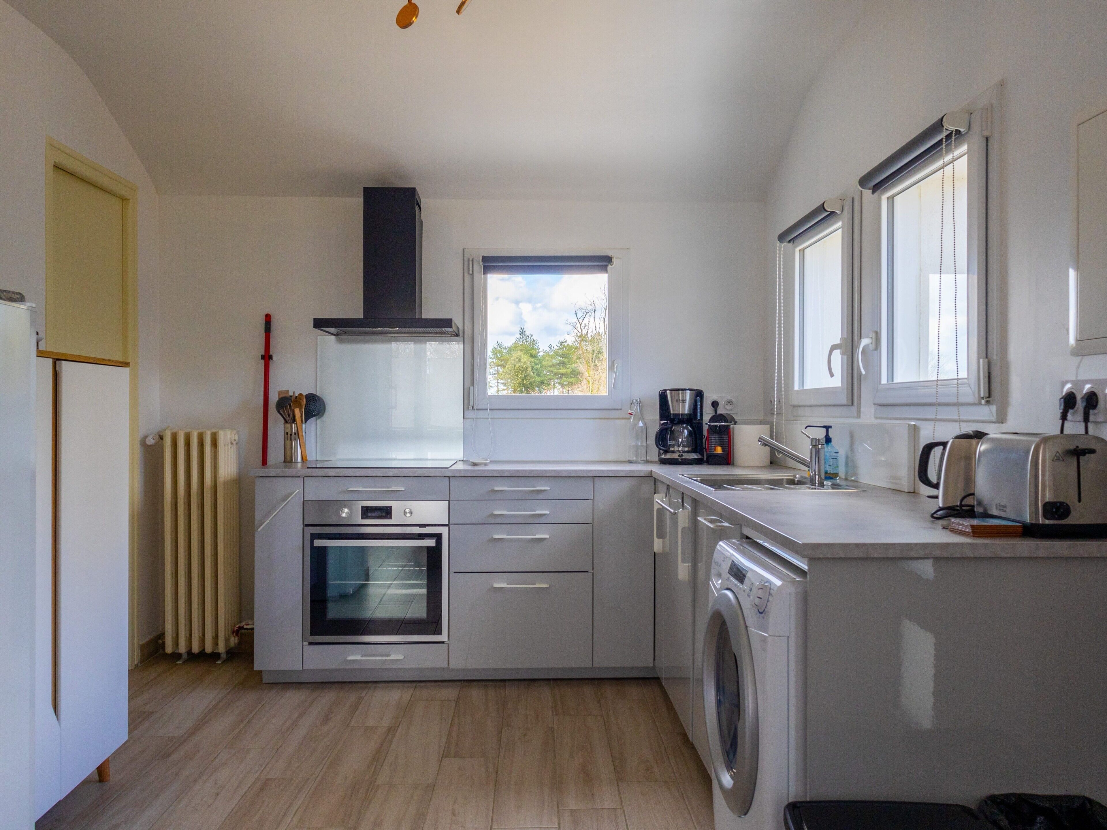 Een moderne keuken met een inbouwoven, een wasmachine en een koffiezetapparaat.