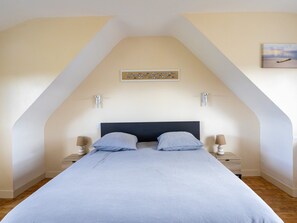 Una camera da letto con un letto, due comodini, un'opera d'arte appesa al muro e un soffitto a falde.