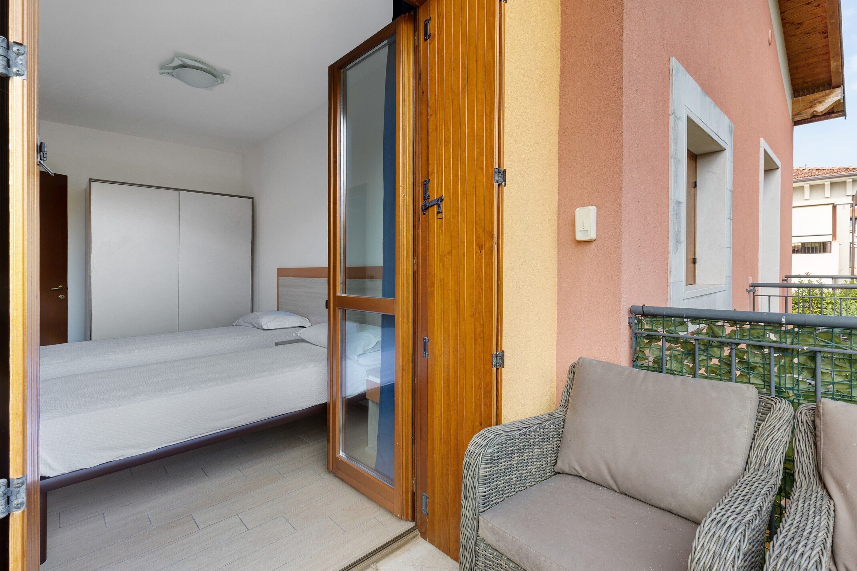 Ein Schlafzimmer mit einem Bett, einer Schiebetür und einem Balkon mit Korbmöbeln.