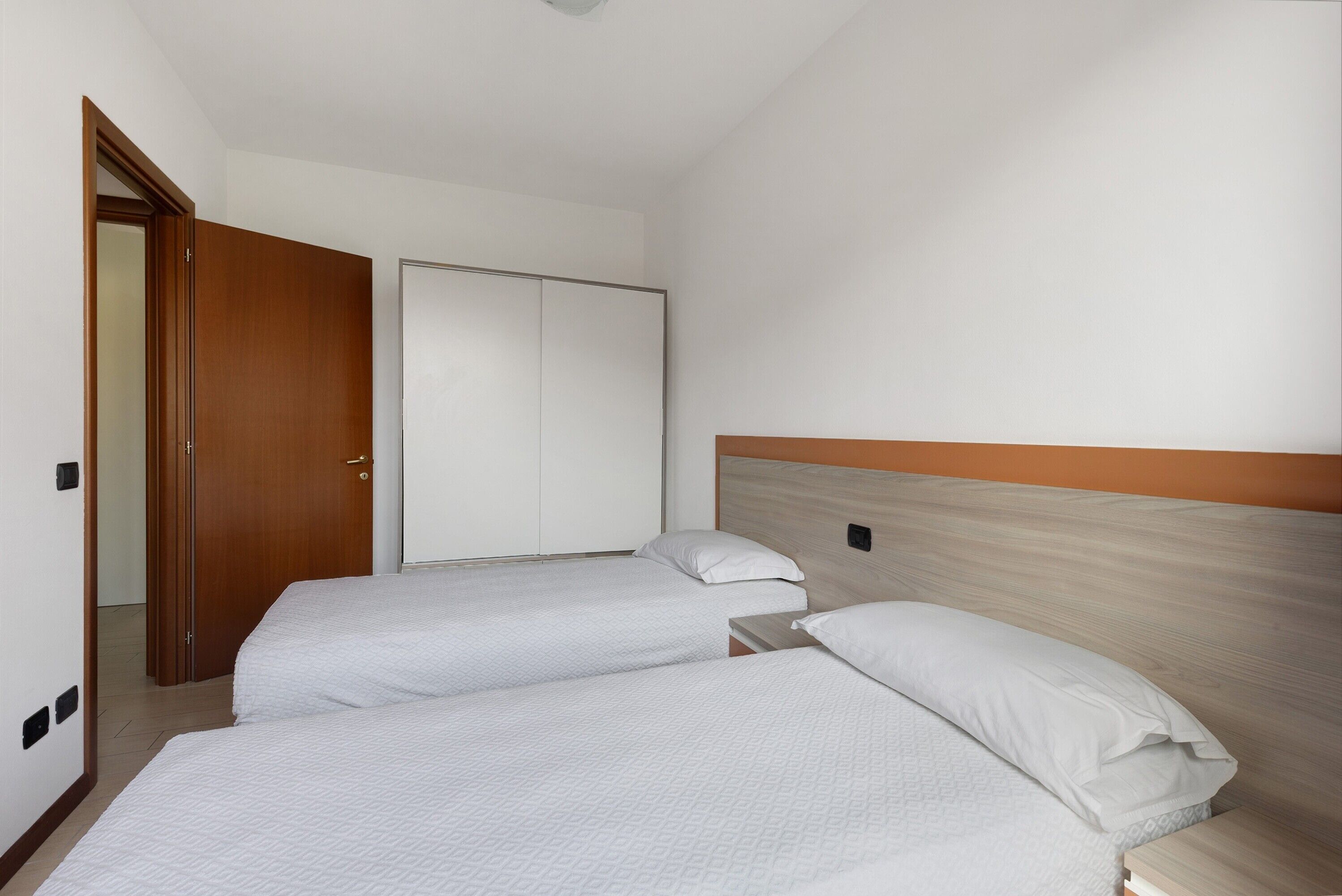 A hotel room with two beds, a wardrobe, and a door.