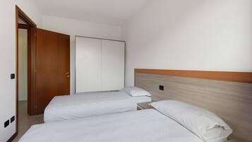 A hotel room with two beds, a wardrobe, and a door.