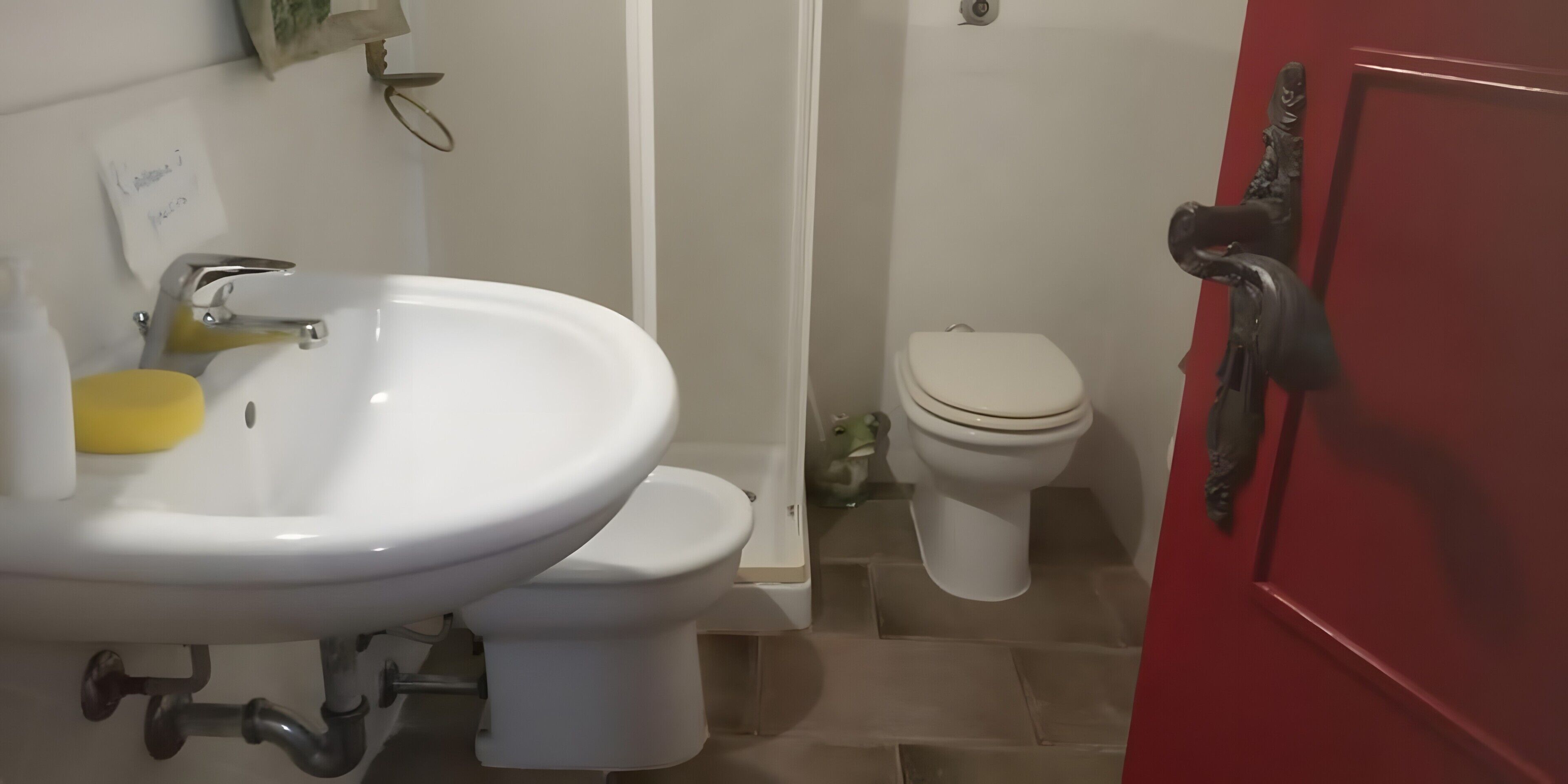 Un baño con un lavamanos blanco, un inodoro y una puerta roja.