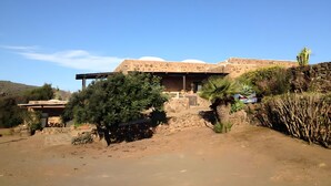 Un edificio de estilo desértico con techo plano, paredes de piedra y un patio cubierto.