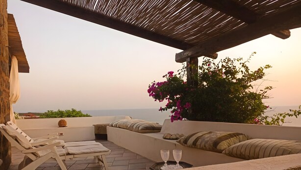 Una terraza con un sofá, sillones de descanso y una mesa con vasos.