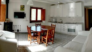 Ett kompakt bostadsutrymme med en matplats, ett litet kök och en sittgrupp.