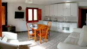 Un espacio habitable compacto con comedor, kitchenette y zona de estar.