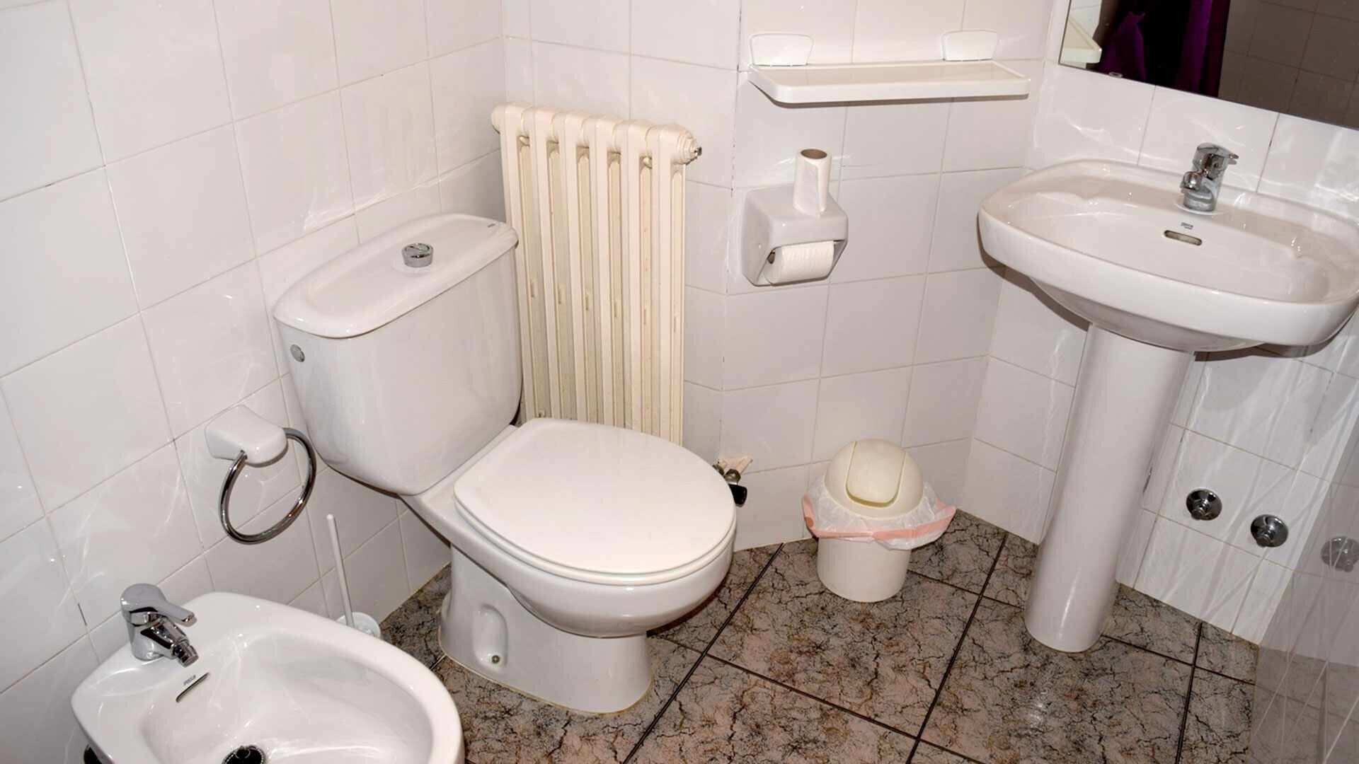 Ett badrum med toalett, bidé, handfat och en handduksdispenser.