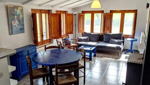 A room with a dining table, chairs, a sofa, and a radiator.