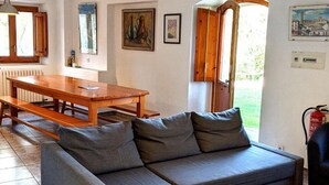 A room with a wooden table, grey sofa, and a window with a view.