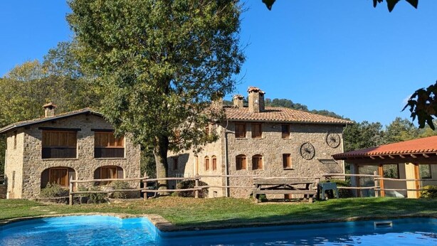 A stone building with a pool, surrounded by trees.