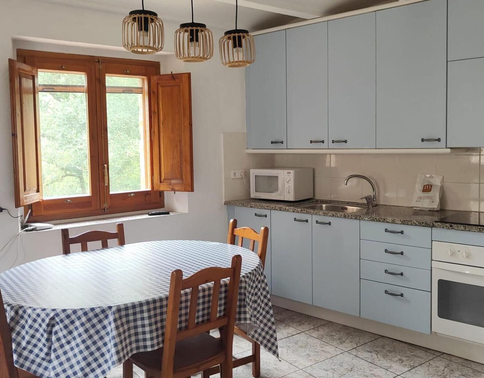 A kitchen with light blue cabinets, a microwave, a sink, and a table with chairs.