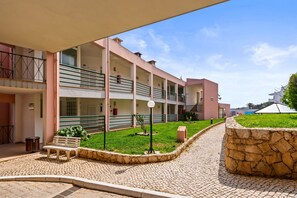 Un cortile con una panchina, un muro in pietra e un edificio con diversi balconi.