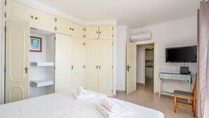 Ett hotellrum med en säng, ett skrivbord med en dator, en tv och en garderob.