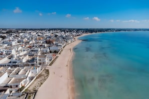 An aerial view of a coastal town with a beach, white buildings, and clear blue waters. - Apartment 'Due Passi Dal Mare Primo Piano' with Sea View, Shared Terrace and Air Conditioning (Torre Lapillo)