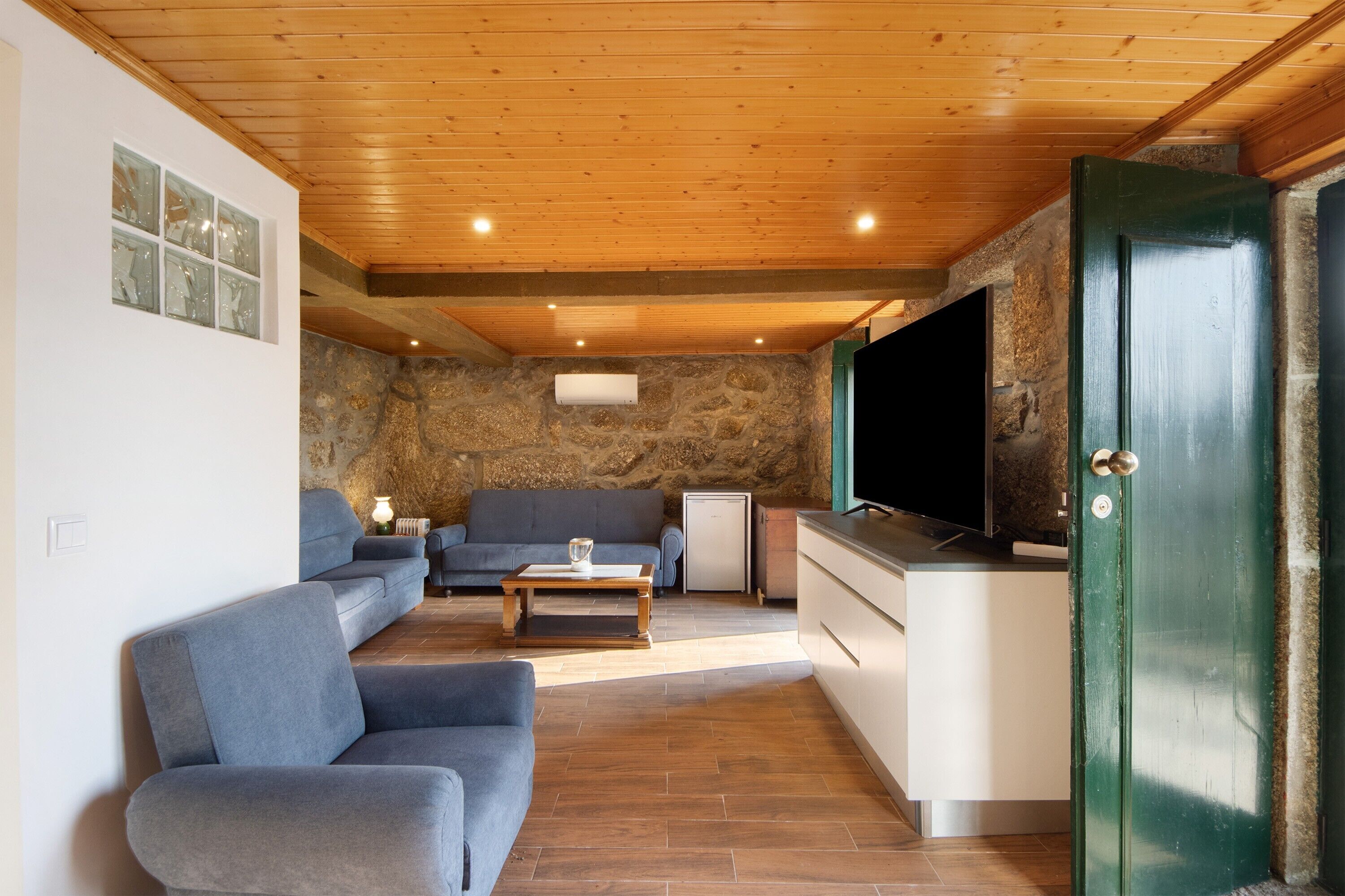 A living room with a sofa, a coffee table, a TV, and a stone wall.