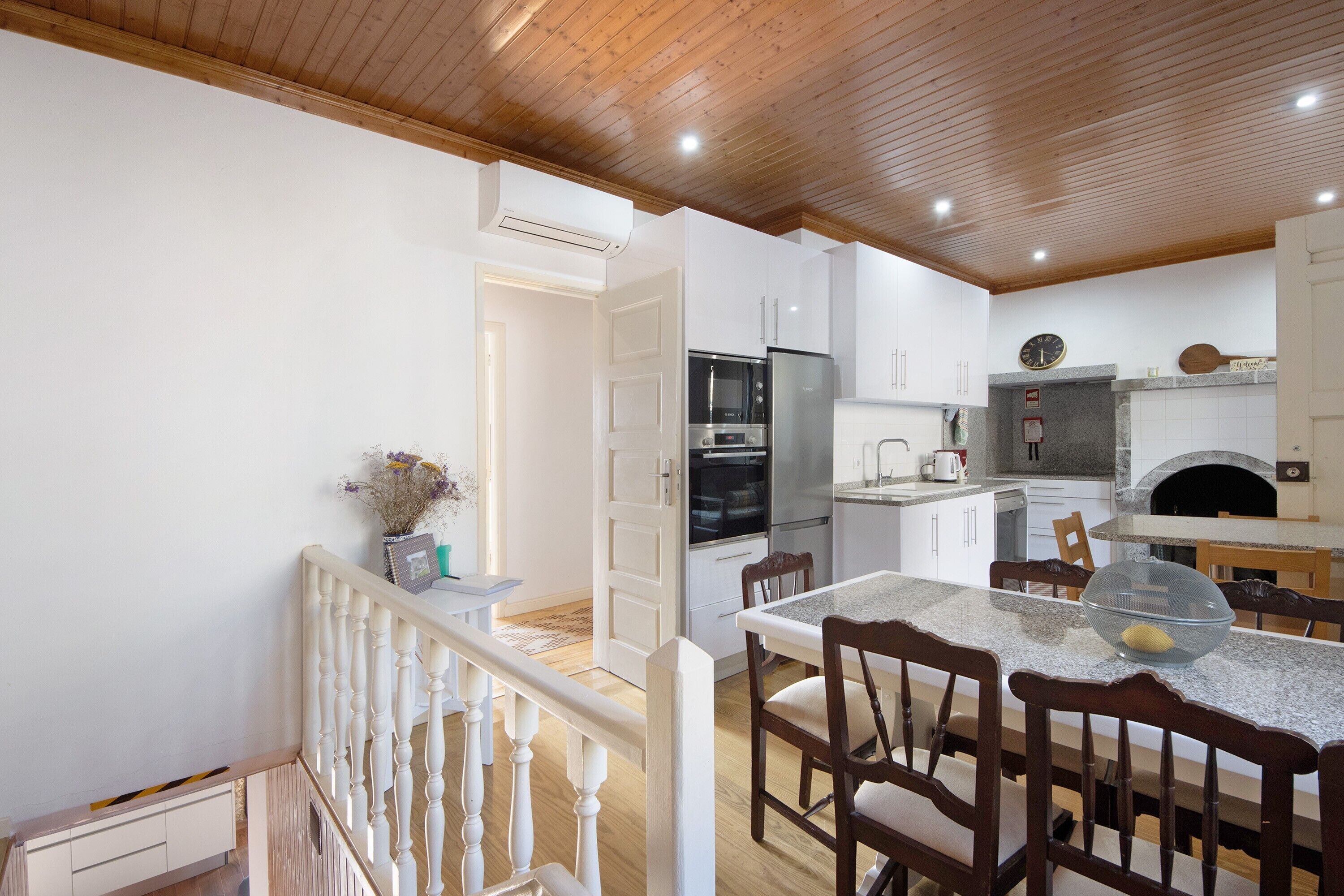 A modern kitchen with white cabinetry, a built-in oven, and a stone countertop.
