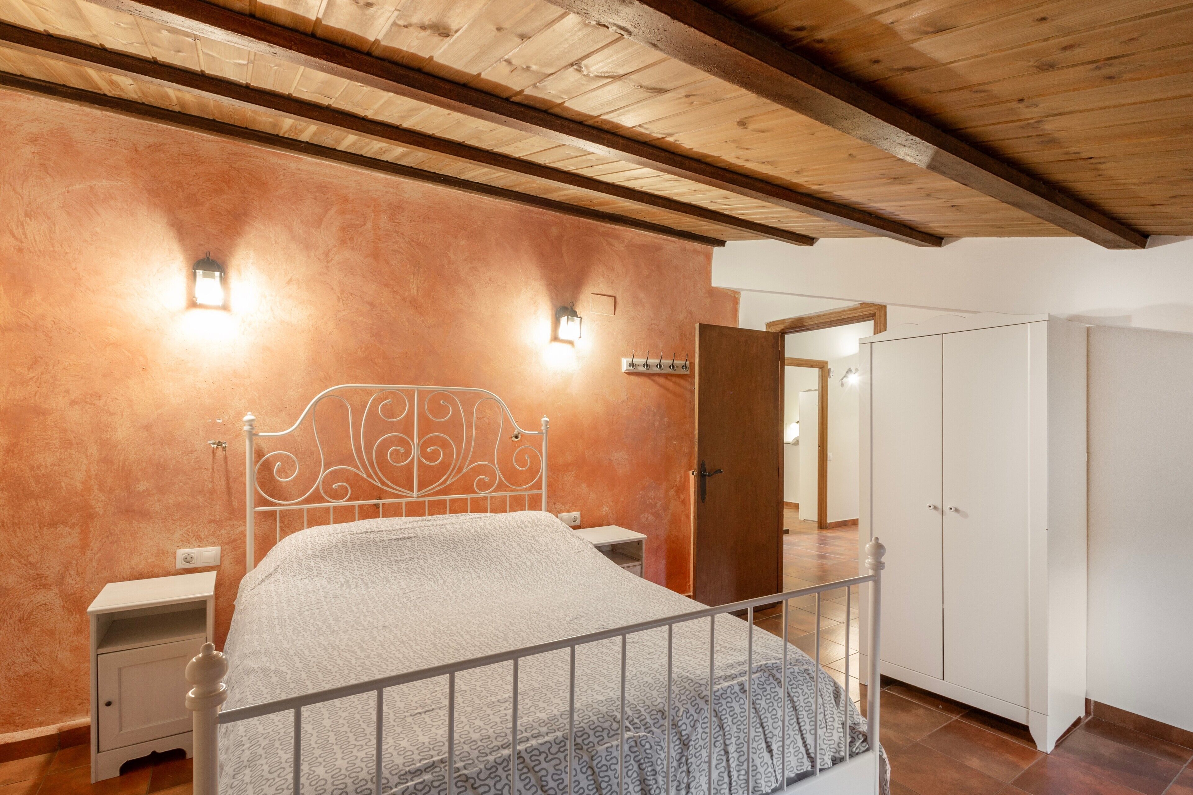 A bedroom with a bed, bedside tables, a wardrobe, and a wooden ceiling.