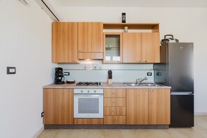 Una cocina con armarios de madera, un refrigerador de acero inoxidable, horno empotrado y estufa a gas.