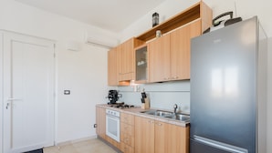 A modern kitchen with wooden cabinets, a stainless steel refrigerator, a built-in oven, and a coffee maker.