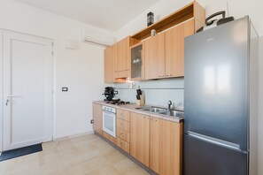 A modern kitchen with wooden cabinets, a stainless steel refrigerator, a built-in oven, and a coffee maker. - Apartment 'Villa Giulia Nord' with Sea View, Wi-Fi and Air Conditioning (Alcamo)