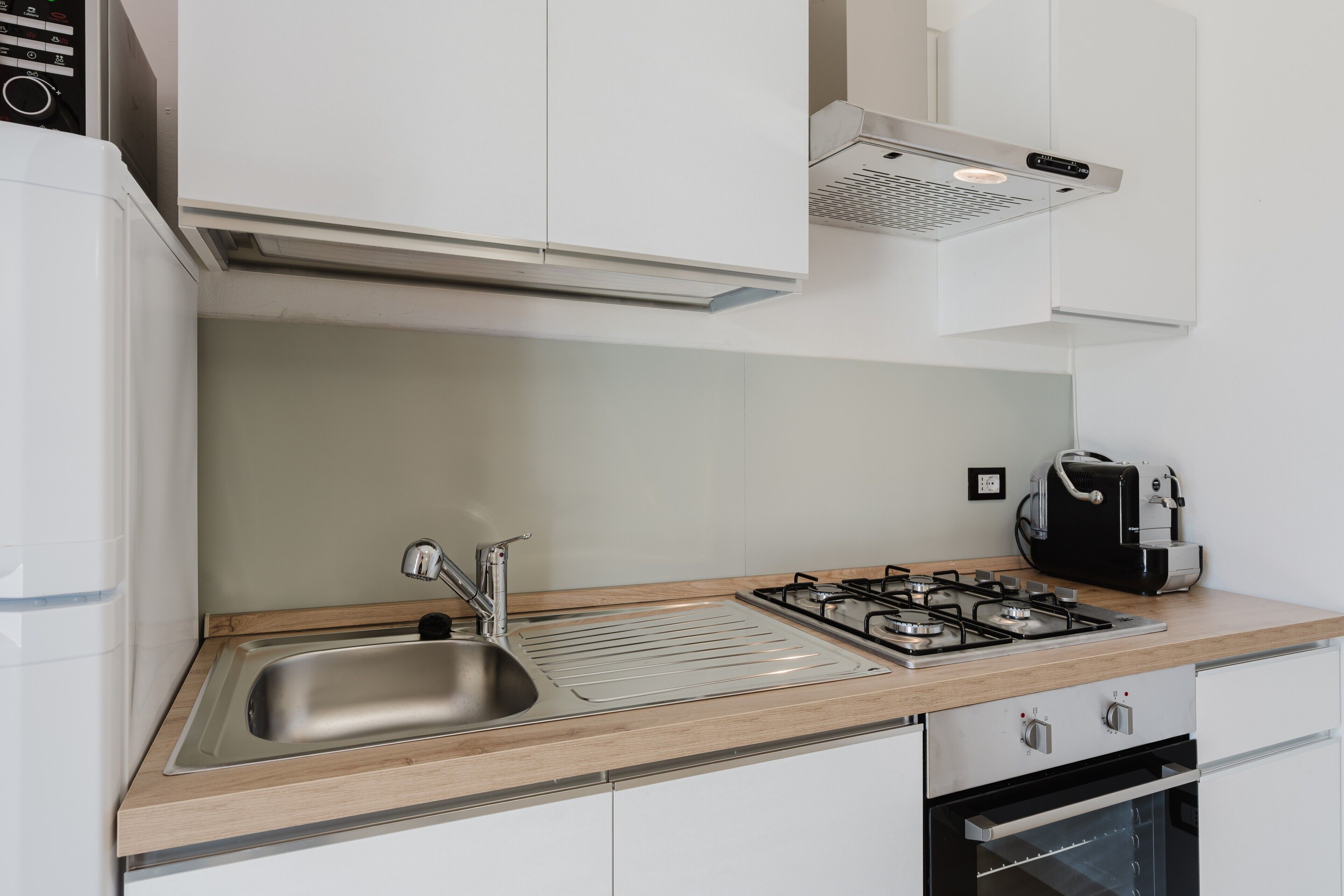 Una cocina moderna con un lavamanos de acero inoxidable, una estufa a gas y un horno empotrado.