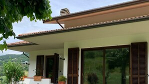 Ein Haus mit überdachter Veranda, großen Schiebegläsern und einem gepflegten Rasen.