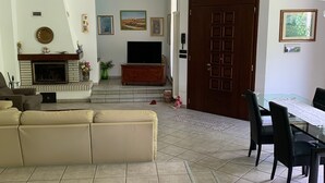 Ein Wohnzimmer mit einer Couch, einem Kamin, einem Fernseher und einem Essbereich mit Tisch und Stühlen.