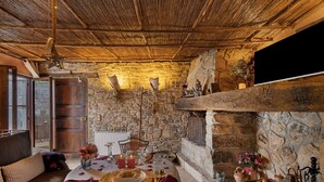 A cozy dining area with a stone wall, a fireplace, and a table set for a meal.
