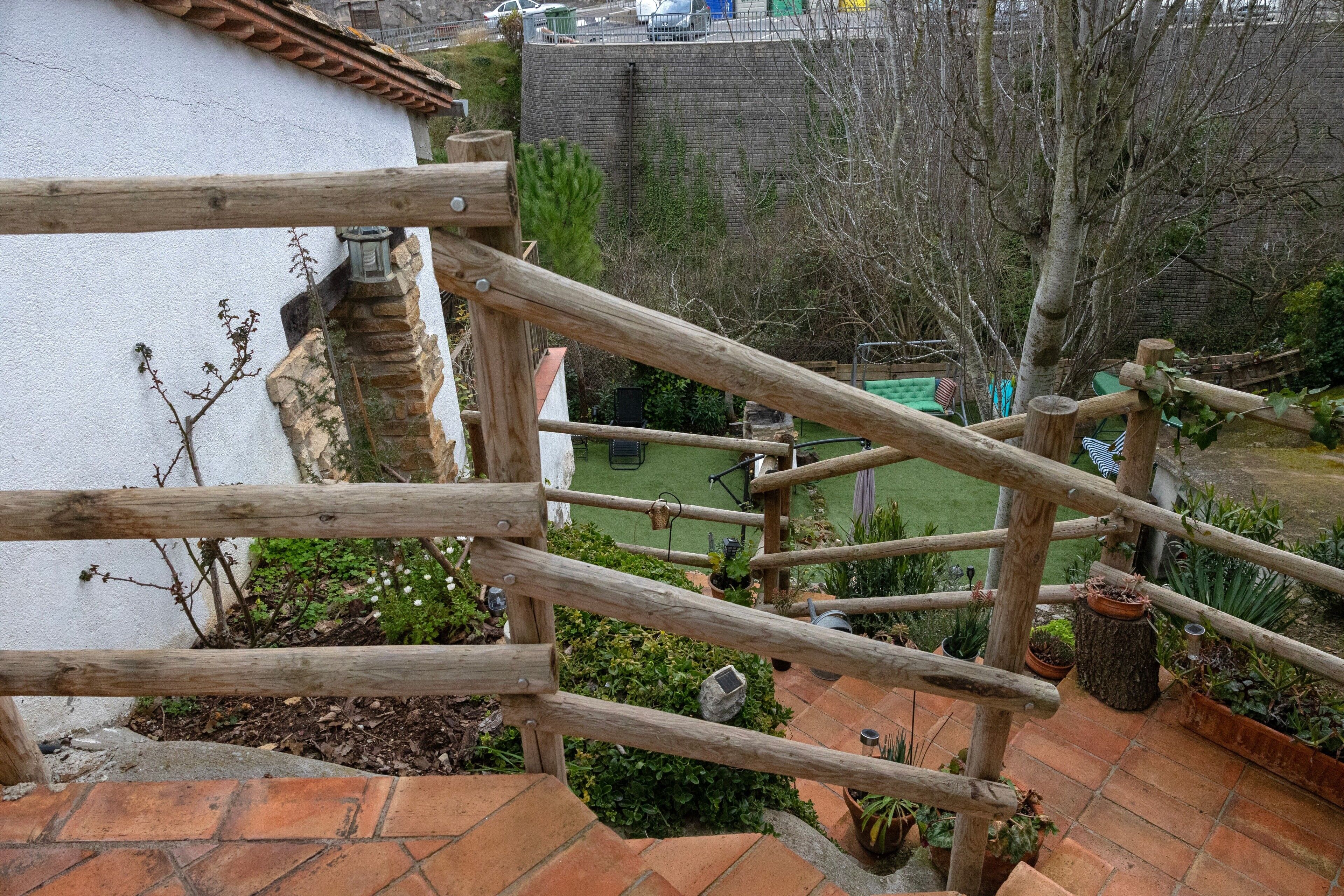 A wooden staircase with a view of a garden and a brick wall.