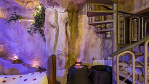 A cave-like interior with a spiral staircase, a small table with a candle, and a barrel.