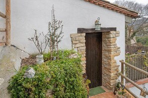 Un edificio rústico con entrada de piedra, puerta de madera y un pequeño porche con un farol.