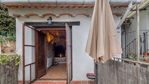 An open wooden door leading to a room with a fireplace, a small table, and a hanging umbrella.