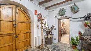A rustic interior with a wooden door, stone flooring, a coat rack, and a potted plant. - Chalet 'Can Pavet' with Mountain View, Private Pool and Wi-Fi (Pontons)