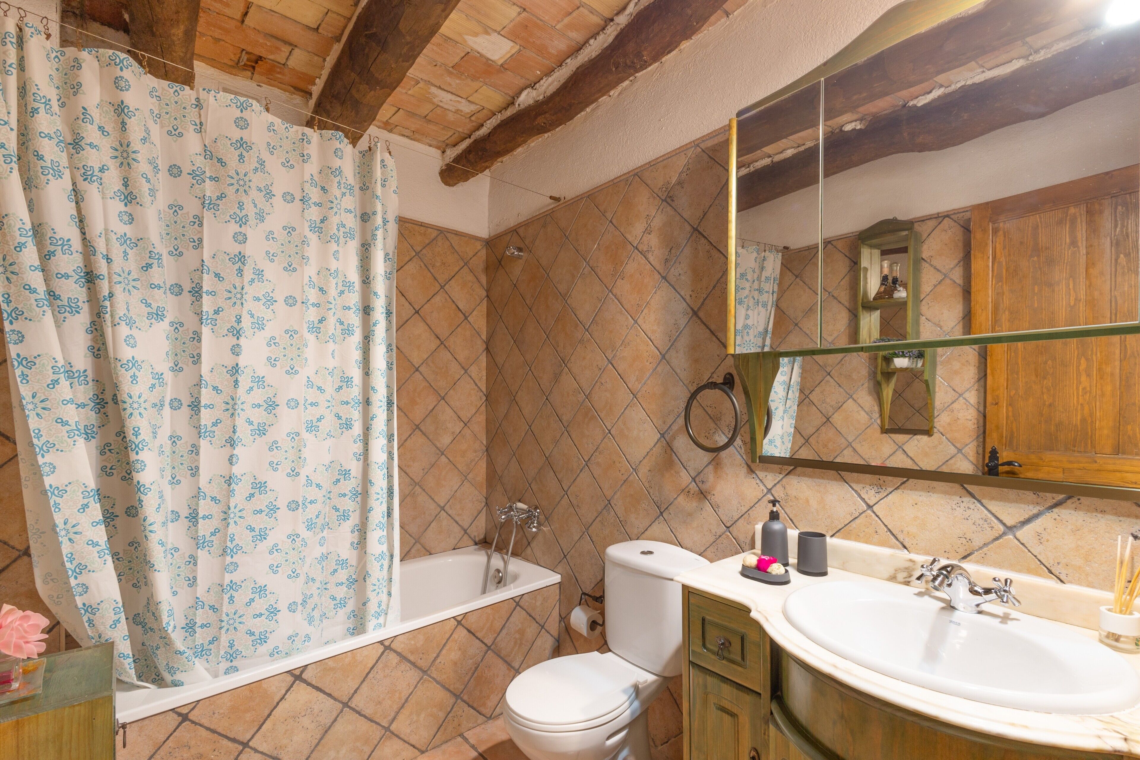 Un baño con ducha, inodoro, lavamanos y espejo.