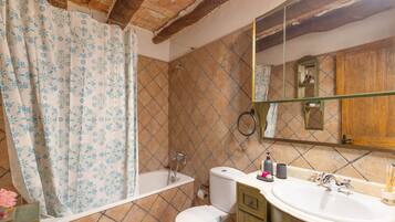 Un baño con ducha, inodoro, lavamanos y espejo.