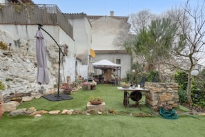 A patio area with a table, chairs, a grill, and a stone wall. - Chalet 'Can Pavet' with Mountain View, Private Pool and Wi-Fi (Pontons)