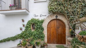A building with a wooden door, potted plants, and a balcony with a railing. - Chalet 'Can Pavet' with Mountain View, Private Pool and Wi-Fi (Pontons)