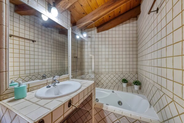 A bathroom with a sink, mirror, and bathtub.