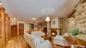 Una sala de estar acogedora con chimenea, un sofá, una mesa de centro y una pared de piedra.