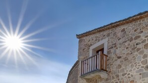 Un edificio de piedra con un balcón bajo un sol radiante.