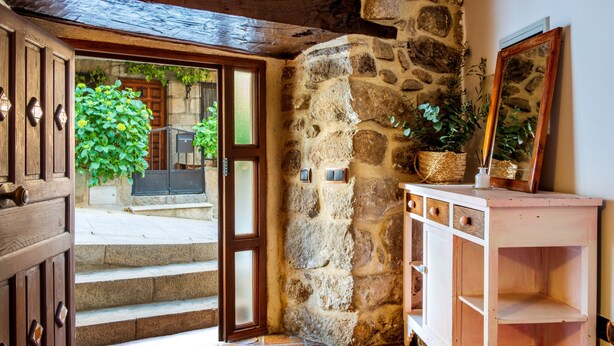 Un muro de piedra, una puerta de madera y un armario blanco con cajones.