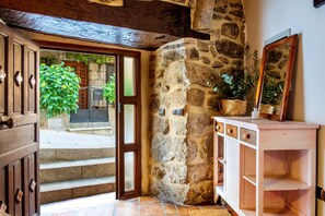 Un mur en pierre, une porte en bois et un meuble blanc avec des tiroirs.