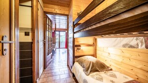 Un pasillo estrecho con paredes de madera y una litera a la derecha.